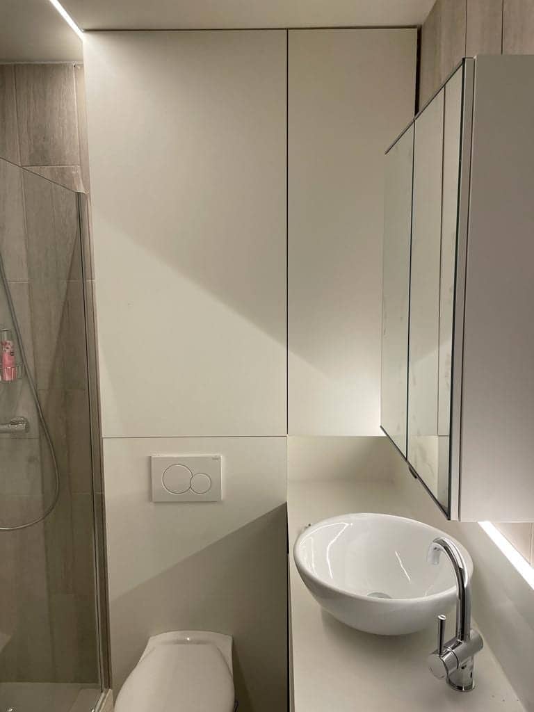 Toiletruimte met hoge witte kasten en waskom