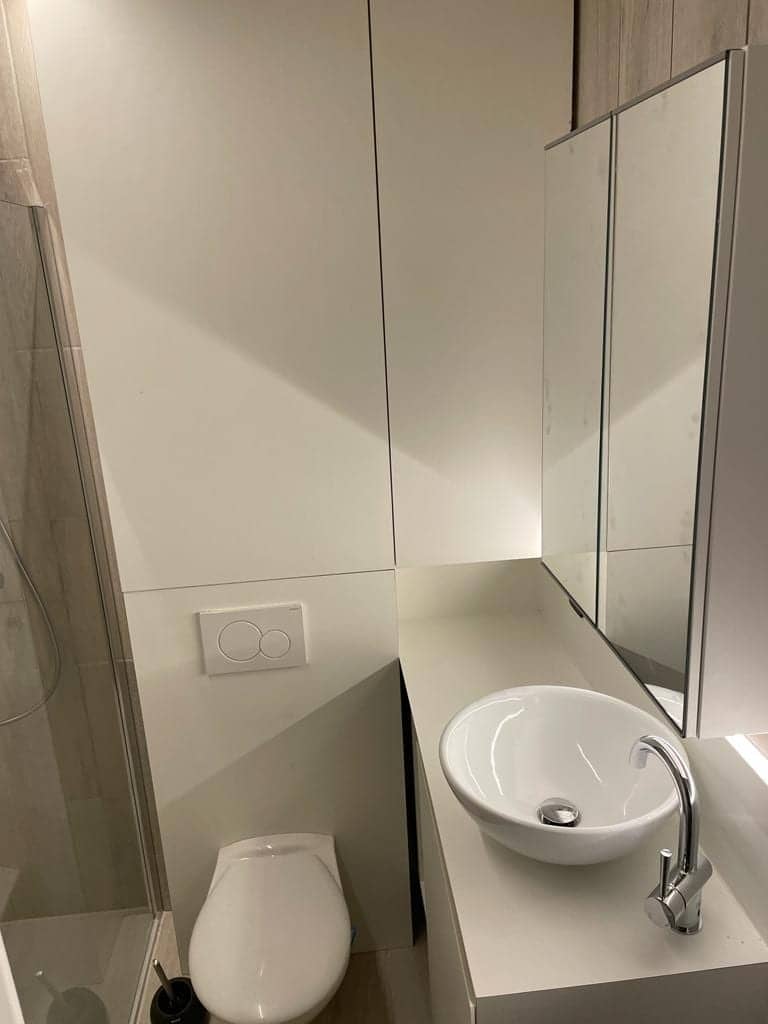 Toilet met smal wastafelmeubel en hoge spiegelkast