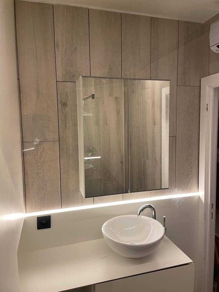 Waskom met verlichte spiegelkast tegen een wand in houtlook