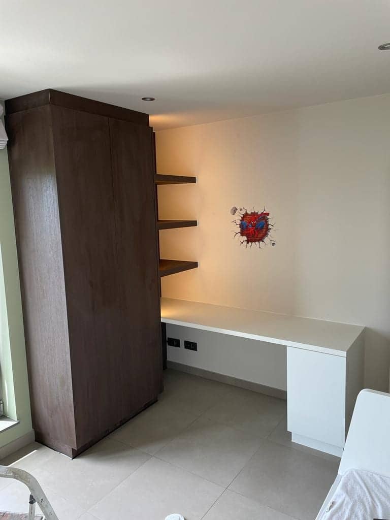 Kinderkamer met hoge kast, verlichte legplanken en bureau
