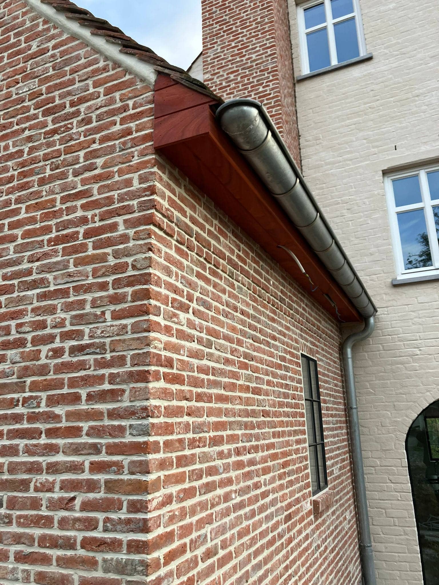 Hoek van de woning met houten goot en zinken afvoer