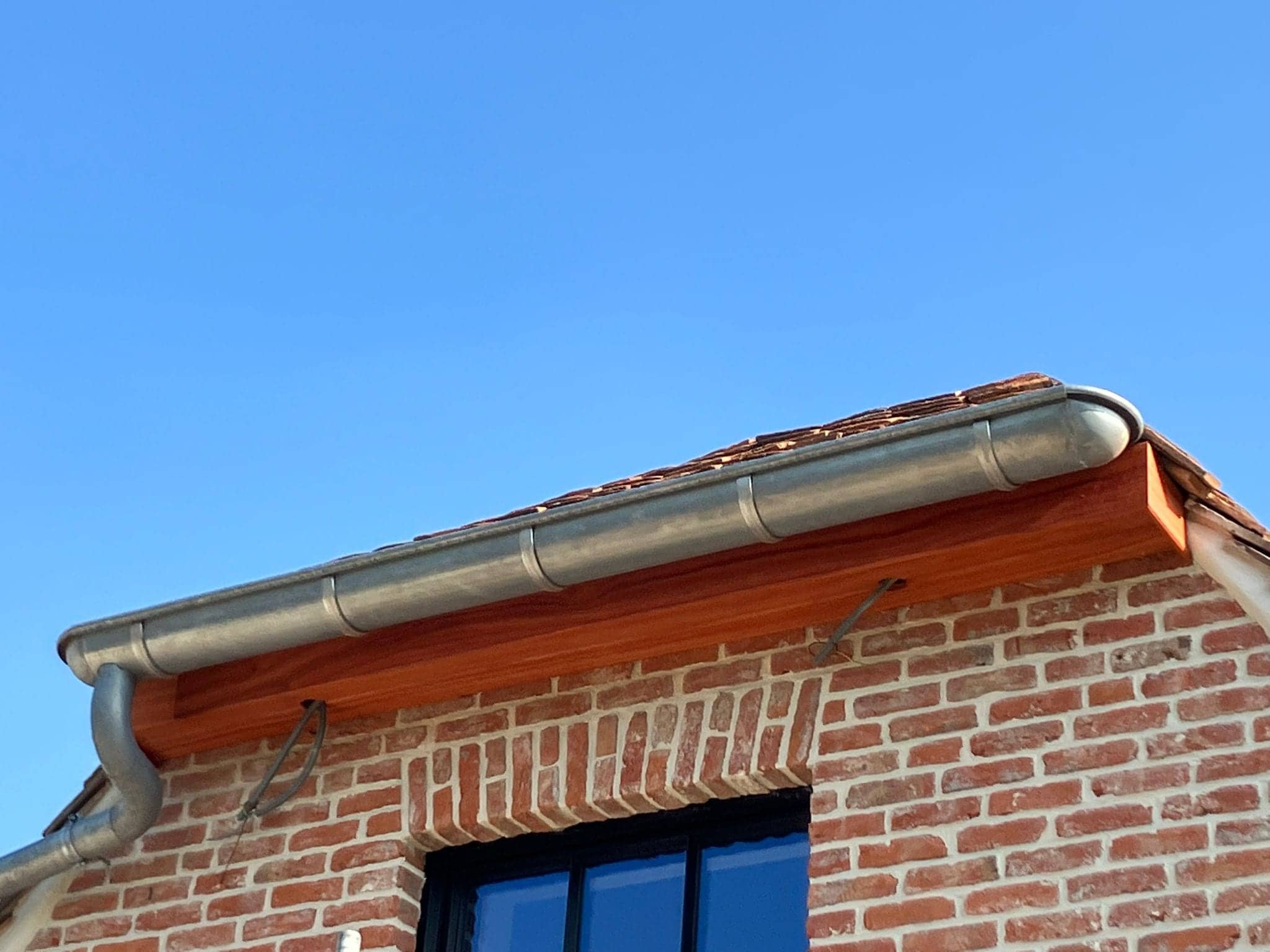 Houten dakoversteek met zinken goot boven een raam
