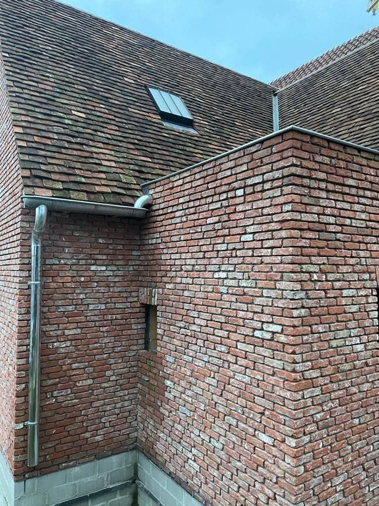 Dakvlakken en zinken goot boven een bakstenen gevel