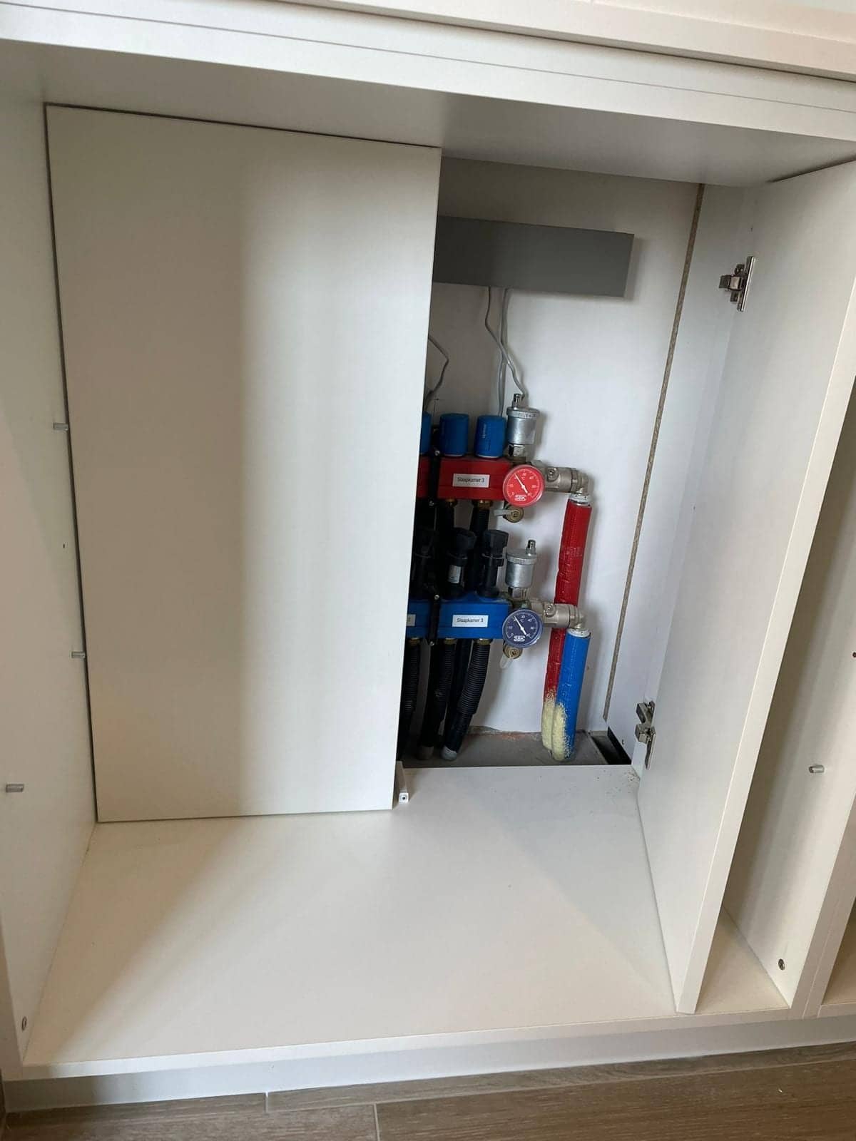 Geopend paneel met de verdeelcollector van de verwarming