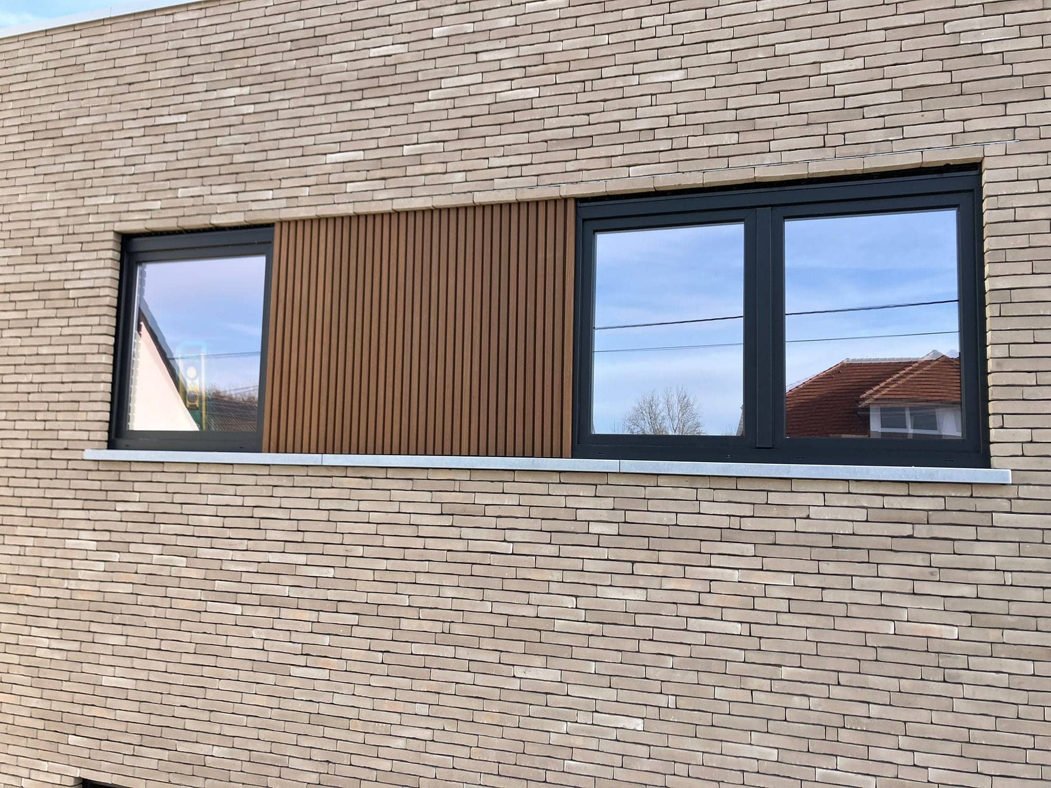 Houten latten tussen twee ramen in een lichte gevel