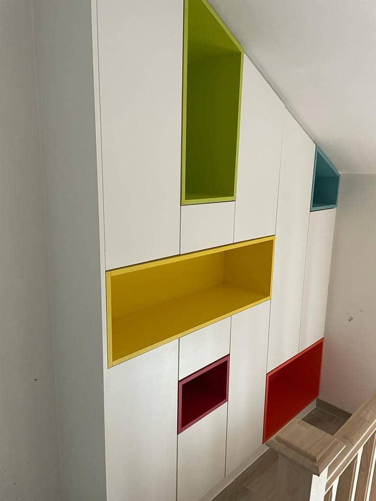 Witte kastenwand met gekleurde nissen in de traphal