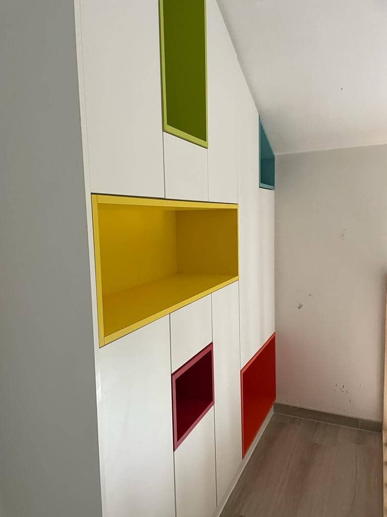 Gele, groene en rode nissen in een witte kastenwand