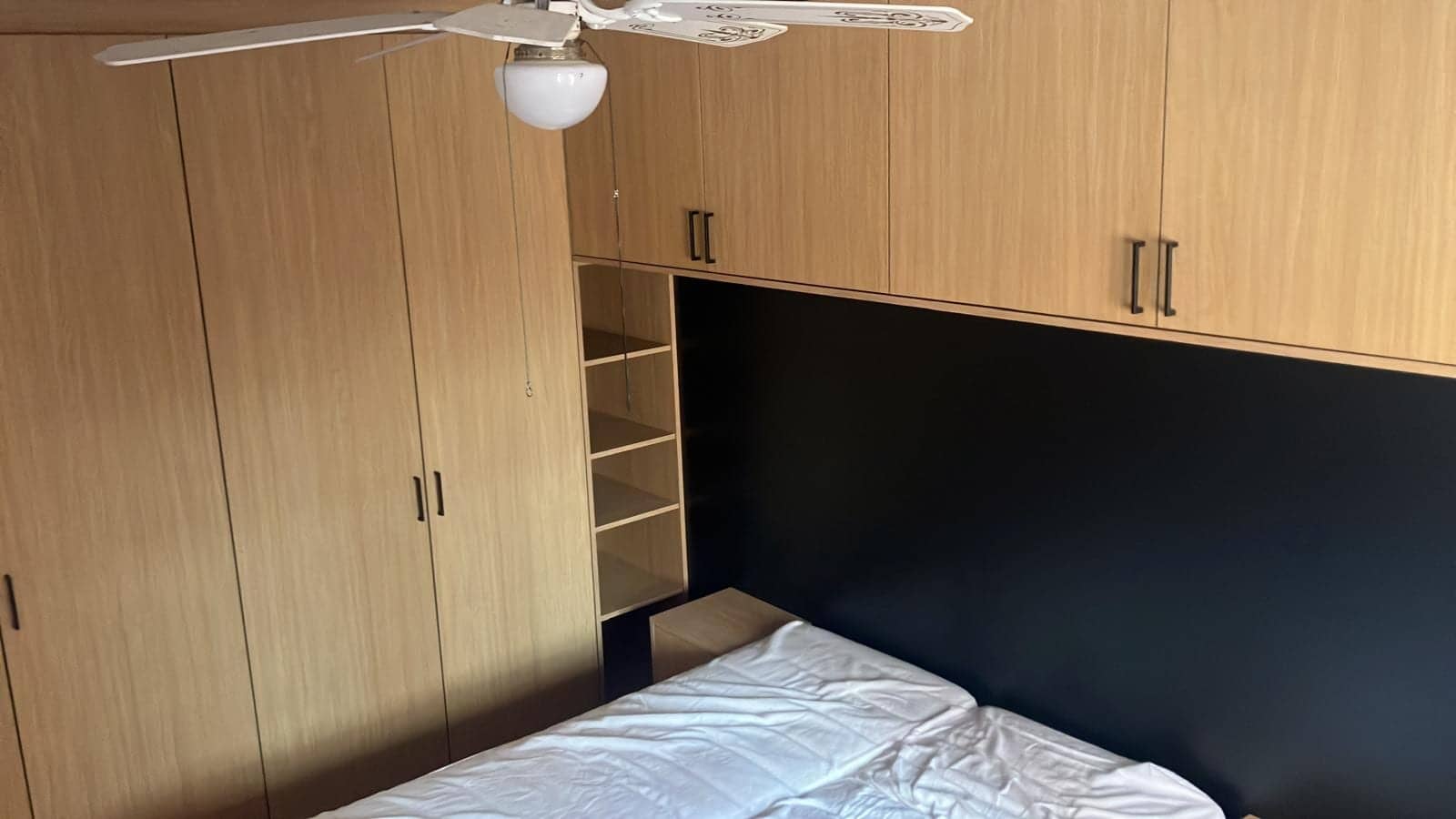 Slaapkamer met hoge kasten en bovenkasten rond het bed