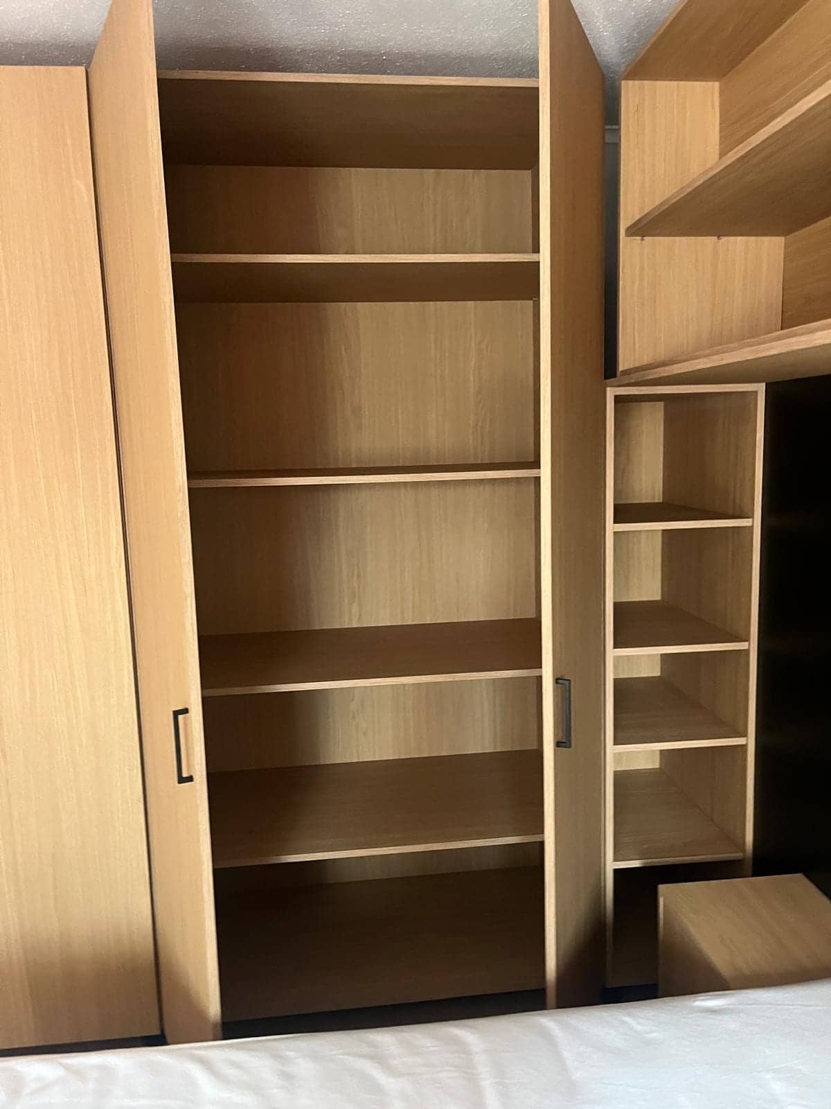 Geopende hoge kast naast een smalle open nis