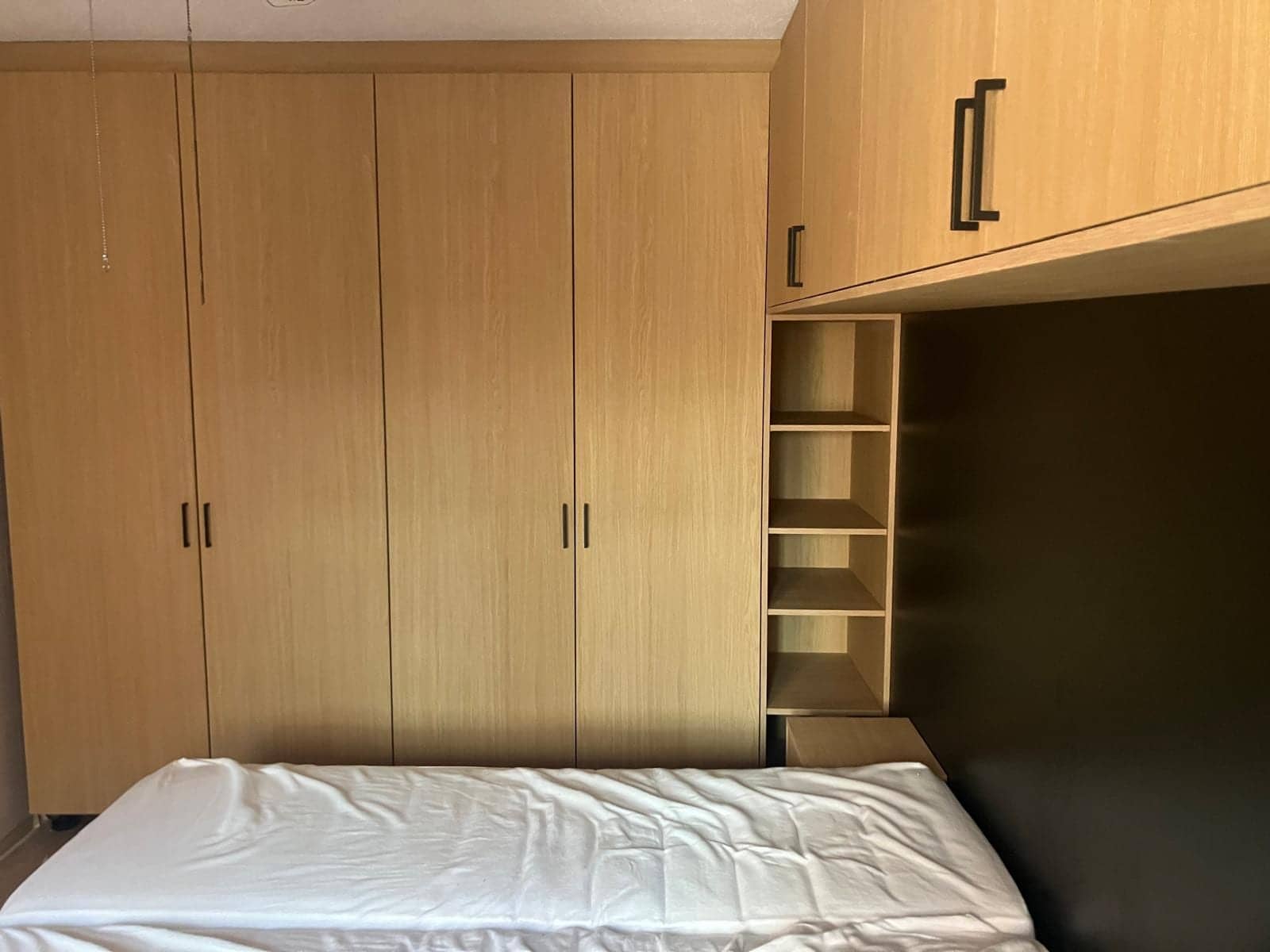 Vier hoge kastdeuren naast een bovenkast boven het bed