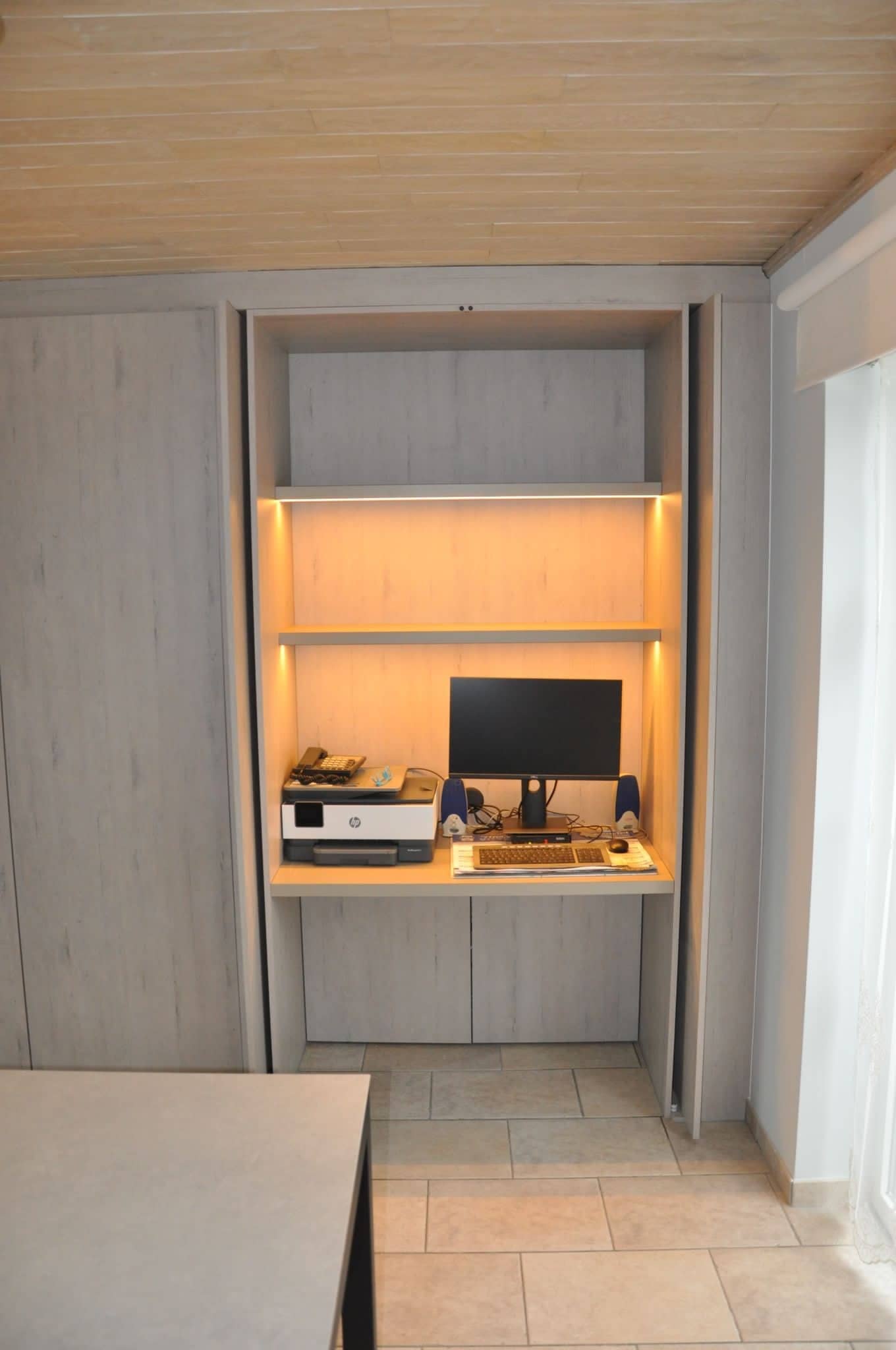 Ingebouwd bureau met verlichting achter geopende kastdeuren