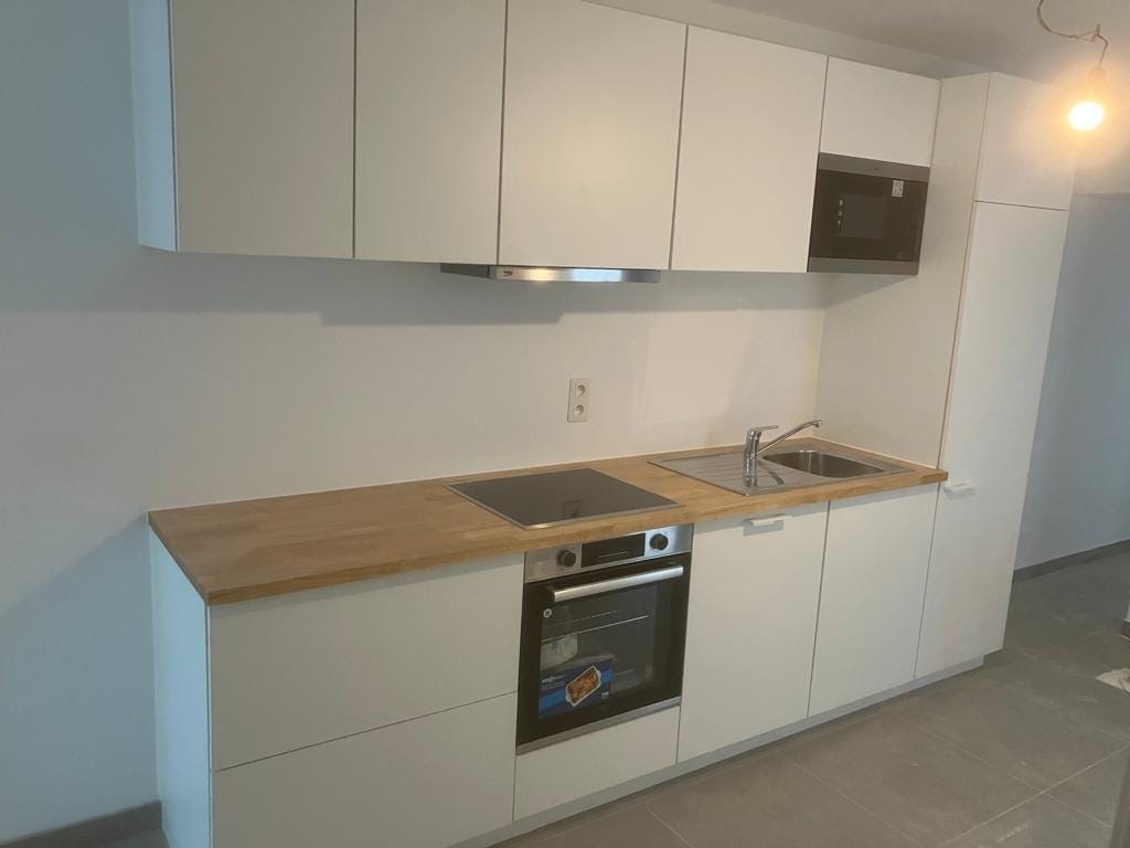 Witte keuken met houten werkblad en bovenkasten