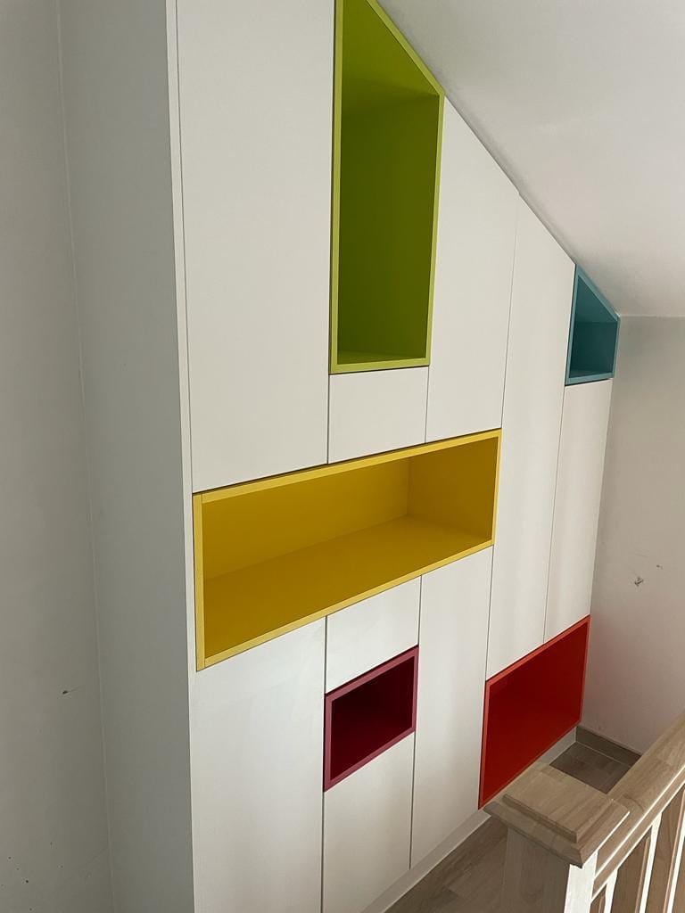 Witte kastenwand met gekleurde nissen in de traphal