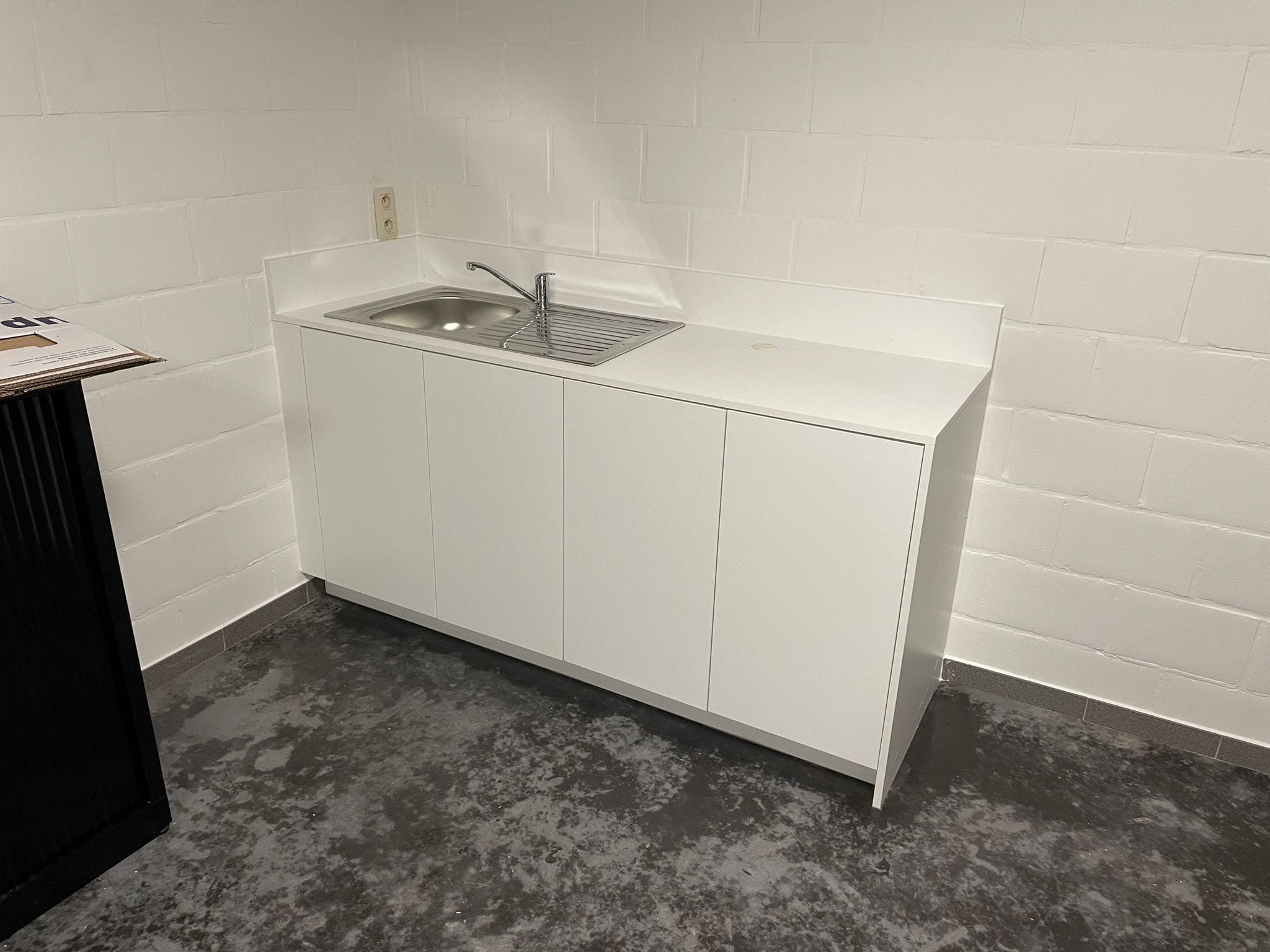 Kleine witte keuken met spoelbak in een bureauruimte