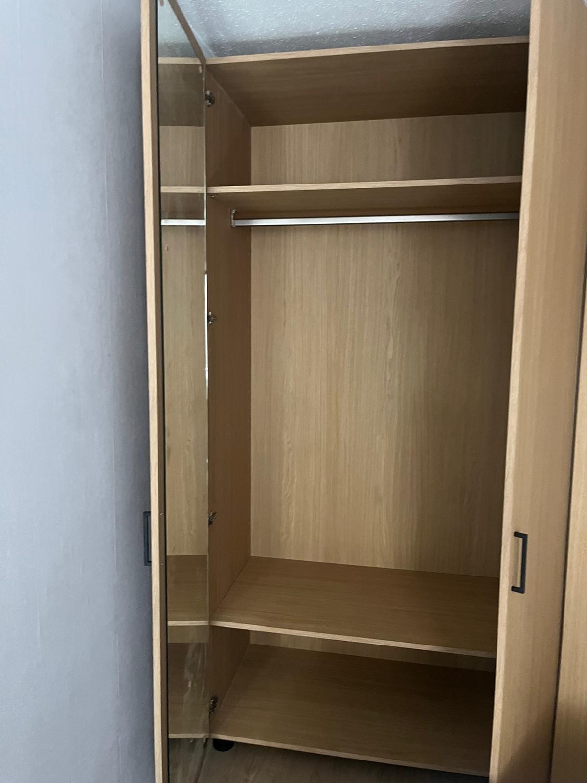 Geopende kleerkast in licht houtdecor met legplanken en hangroede