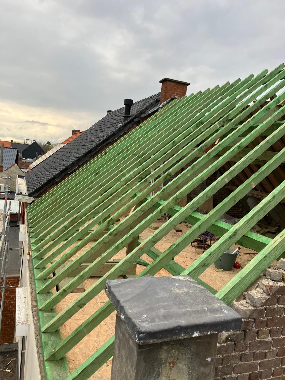 Nieuwe kepers van een zadeldak tussen de buurhuizen