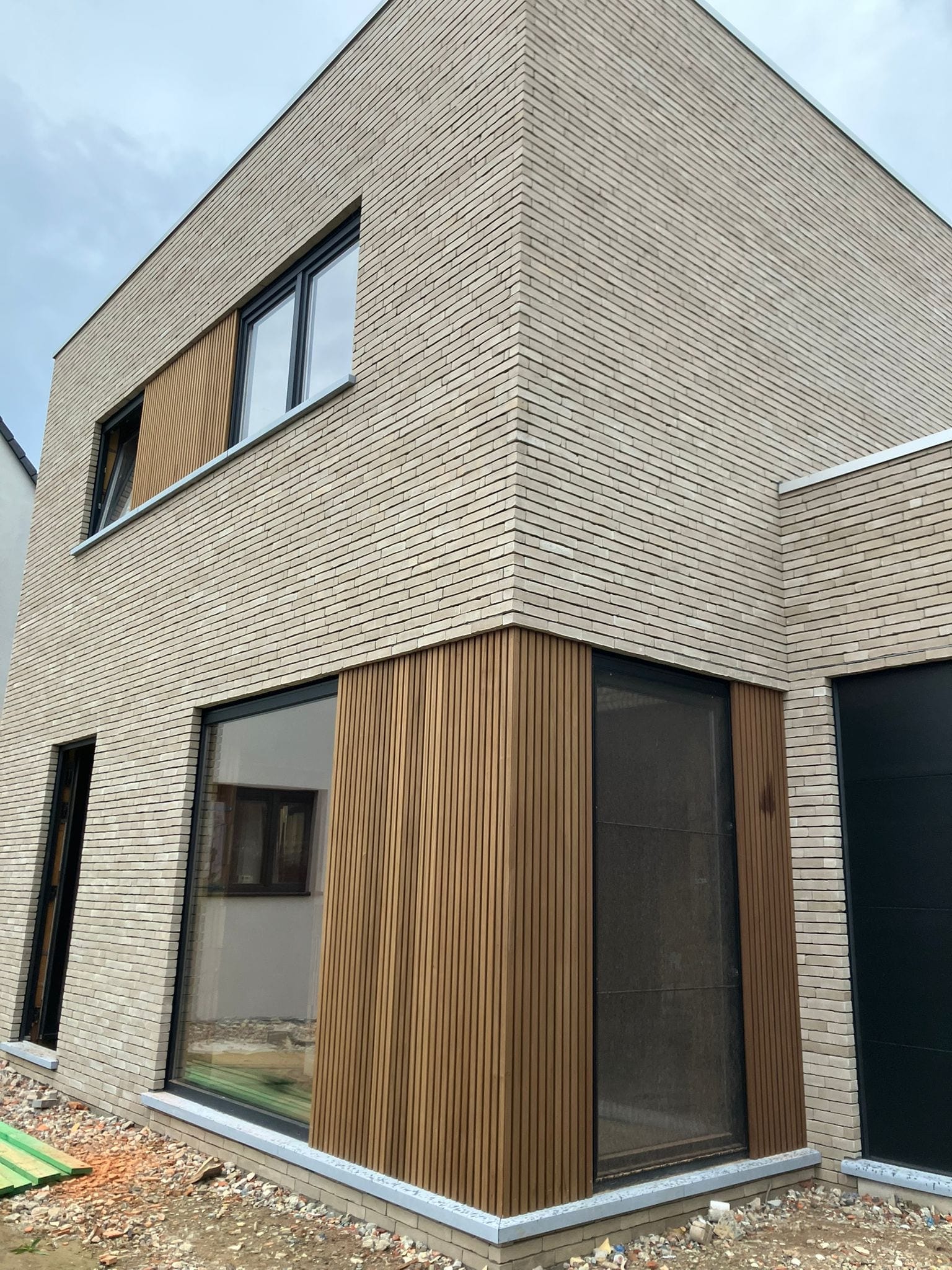 Hoek van de woning met houten gevelbekleding rond de ramen